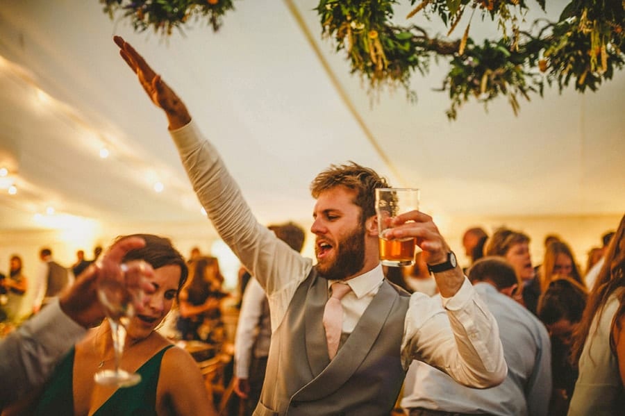 An usher dancing on the dancefloor with a drink in his hand