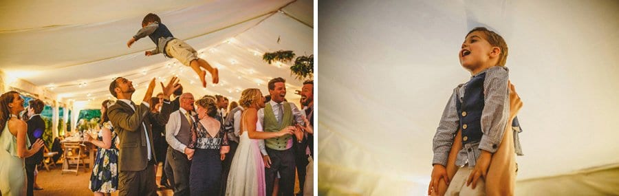 A little boy is thrown in the air by his father in the marquee