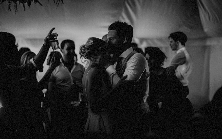The groom kisses his bride on the dancefloor in the marquee