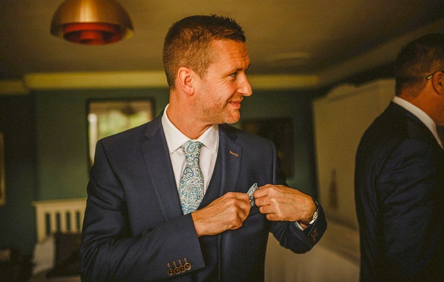 The groom positions his flower on his suit jacket
