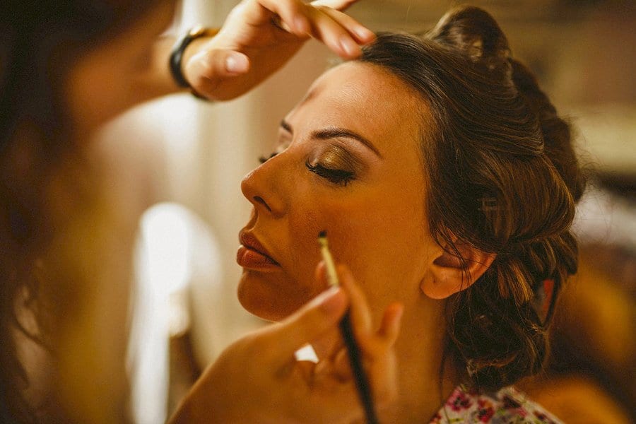 The make up artist applies eye liner to the brides eyelashes