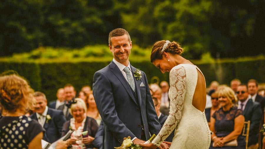 The bride laughs and looks to the ground as the groom smiles and looks away during the outdoor ceremony