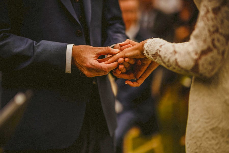 The groom places the wedding ring on the finger of the bride during the outdoor ceremony