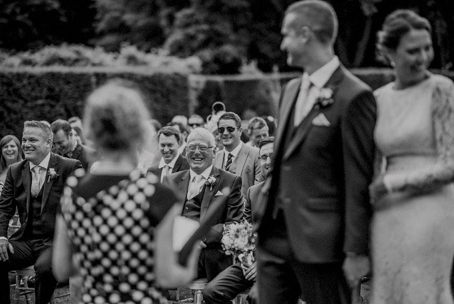 The grooms father and best man laugh during the outdoor wedding ceremony
