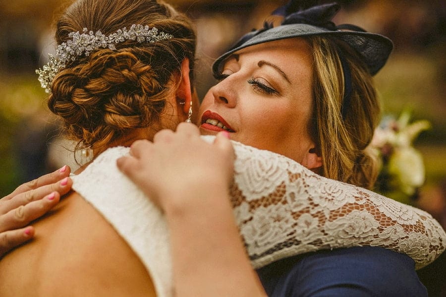 A wedding guest embraces the bride at the end of the outdoor wedding ceremony