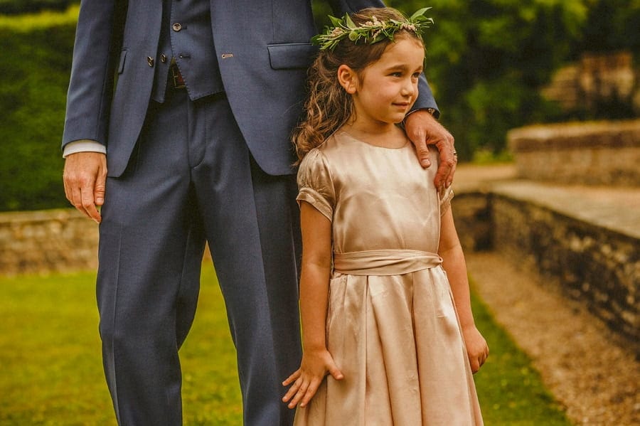 A flower girl stands next to the groom on the front lawn at Voewood House in Norfolk