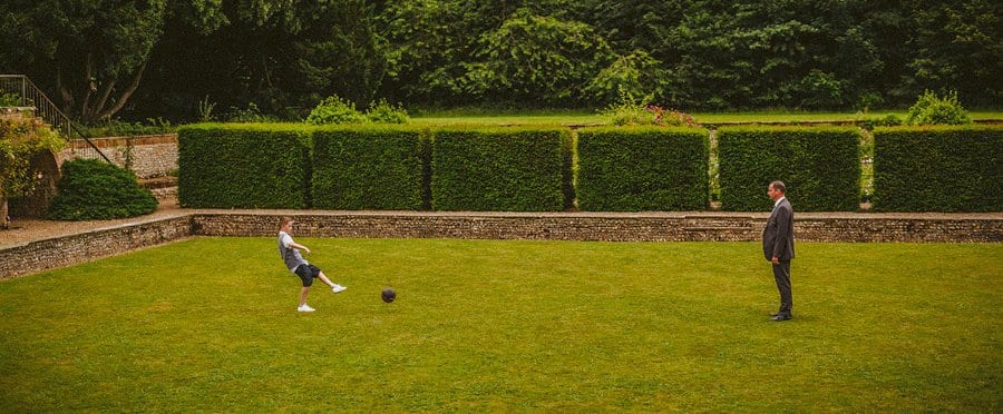 A boy kicks a football towards his father on the lawn at Voewood
