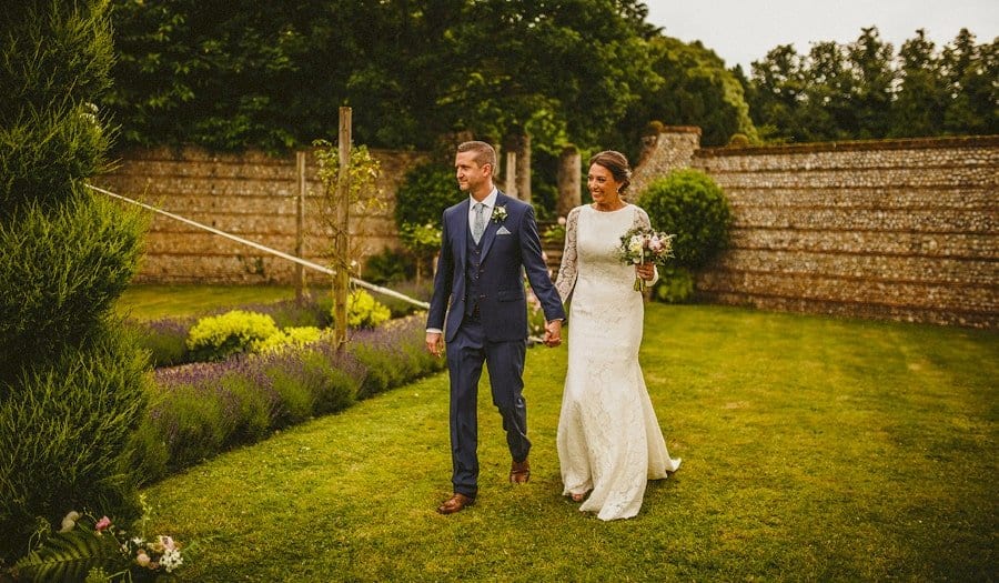 The bride and groom walk towards the marquee at the back of Voewood house