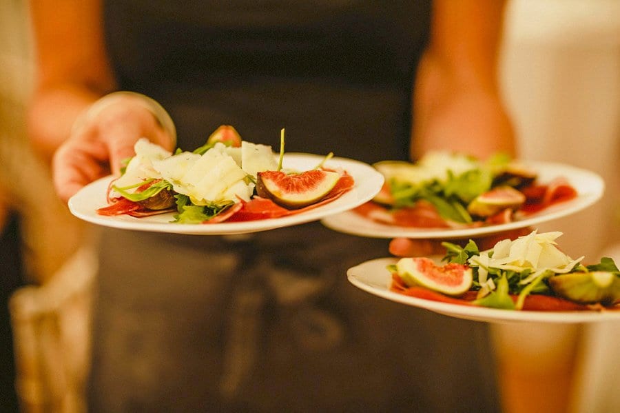 A waitress holds plates of fruit in the marquee