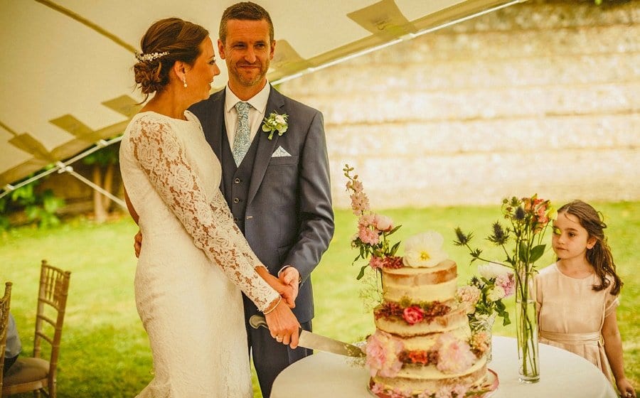 The bride and groom cut the cake in the marquee at Voewood