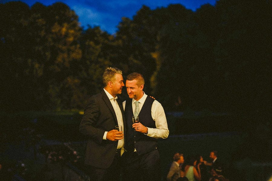 The groom chats with a friend at the back of Voewood House in Norfolk