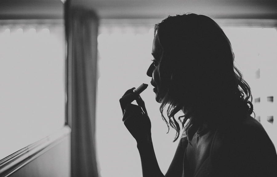 A bridesmaid puts lipstick on in the mirror