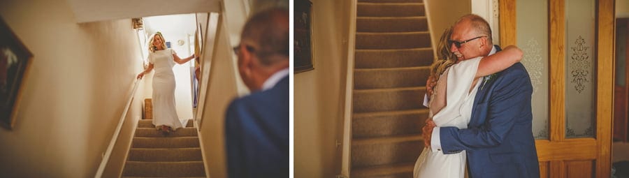 The bride walks down the stairs of her parents house and greets her father
