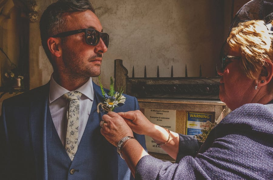 The brides mother adjusts the flower lapel on the grooms jacket