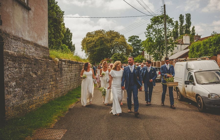 The bride and groom leave the church and walk down the street