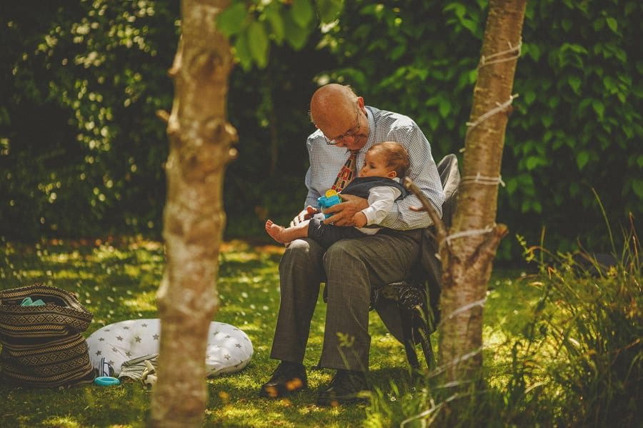 A man holds his great grandson in the garden