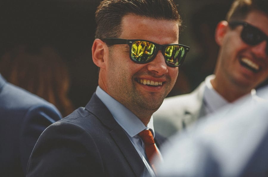 A man with sunglasses smiles at the bride and groom