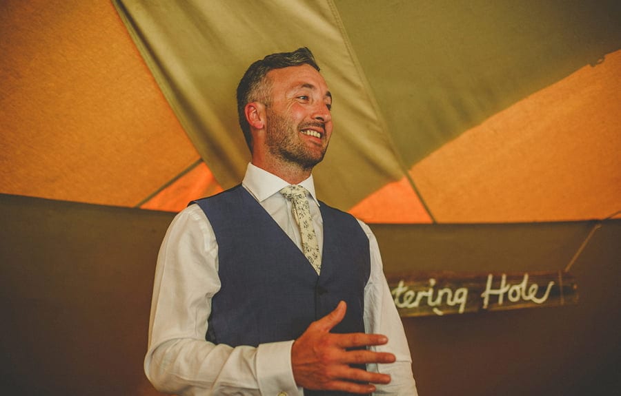 The groom shares a joke with everyone in the tipi