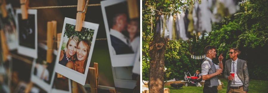 A polaroid photograph hangs on a piece of string with a page attached to it and wedding guests chat in the garden