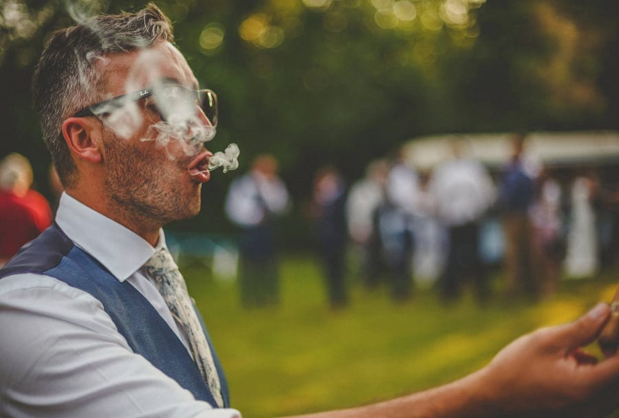 The groom exhales smoke from a cigar