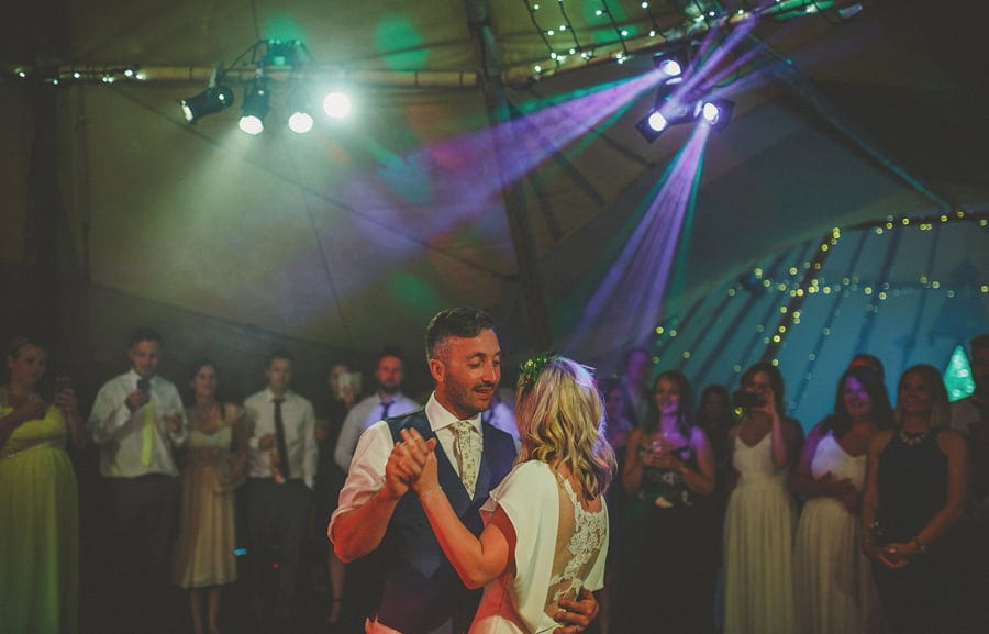 The groom smiles at the bride on the dancefloor during the first dance
