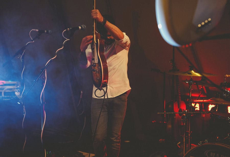 The guitarist of the wedding band on stage of the tipi performing a song