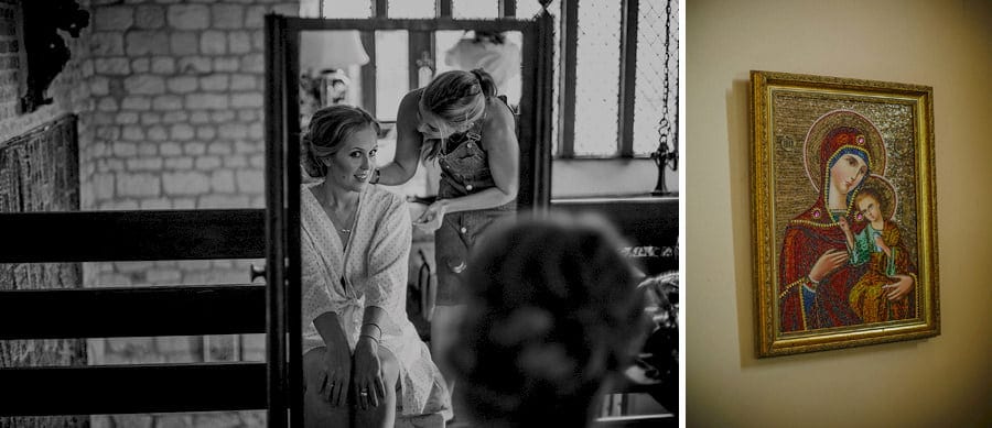 The bride looks in the mirror as the hair stylist pins the back of the brides hair in the old barn