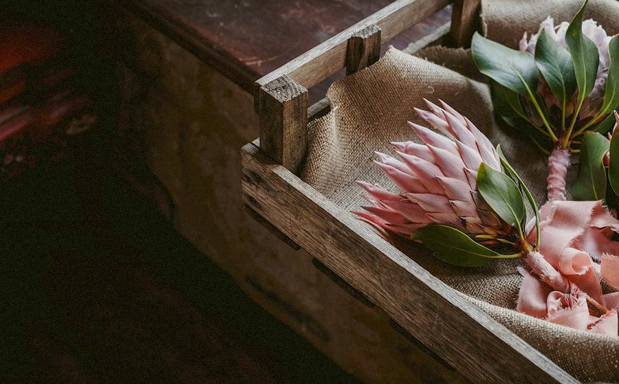 The brides pink wedding flowers in a wooden box rest on cloth