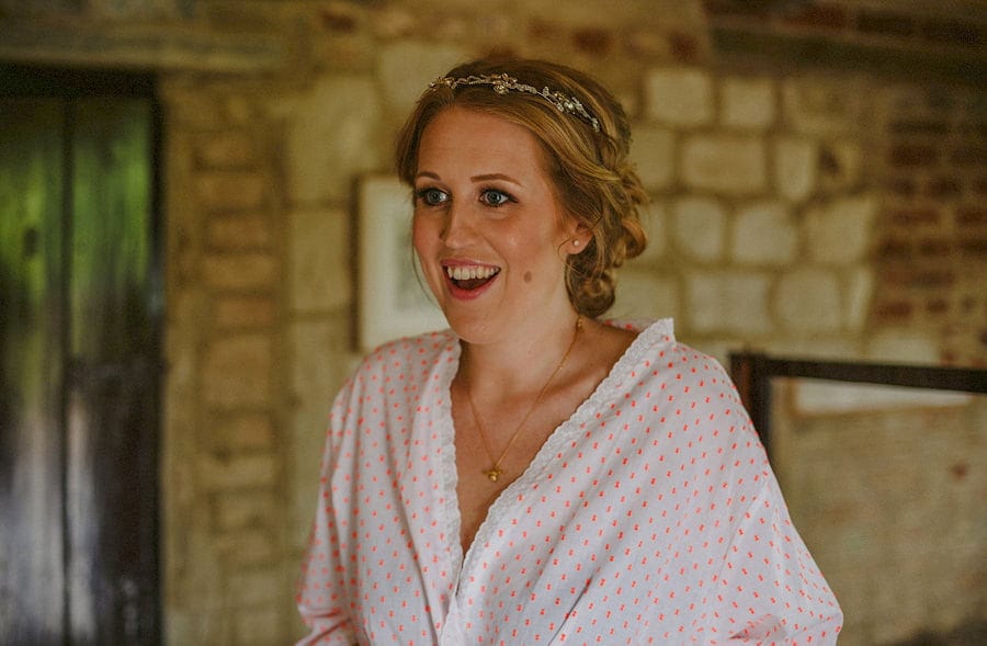 The bride smiles as she listens to her bridesmaid in the old barn