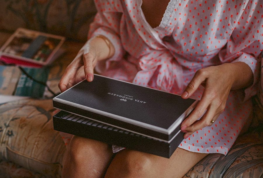 The bride opens a black box which is resting on her lap in the old barn