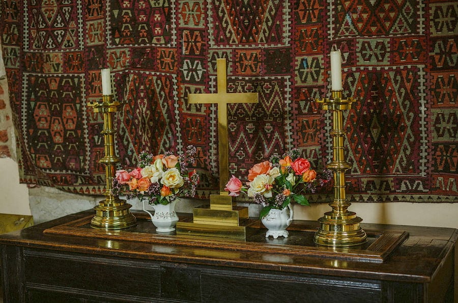 A gold cross and candles rest on a large wooden cabinet in the chapel at Childerley