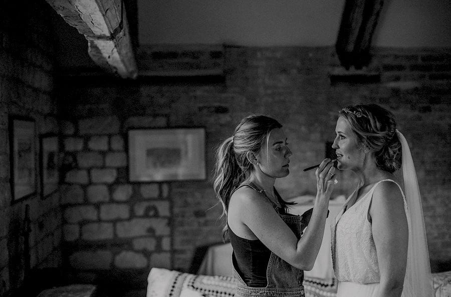 The makeup artist applies lipstick to the brides lips