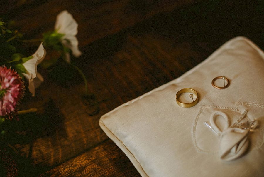 The wedding rings lay on a cream cushion