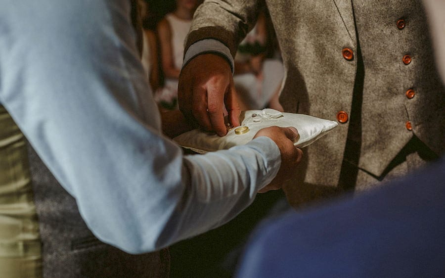 The groom takes a wedding ring from the cushion during the wedding ceremony