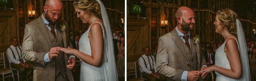The groom places a ring on the finger of the bride during the wedding ceremony in the old barn