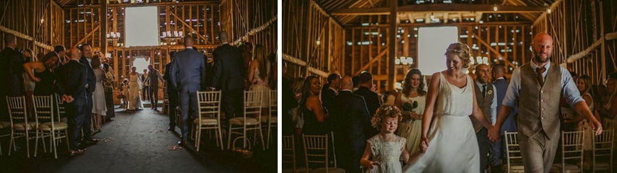 The bride and groom walk hand in hand out of the old barn
