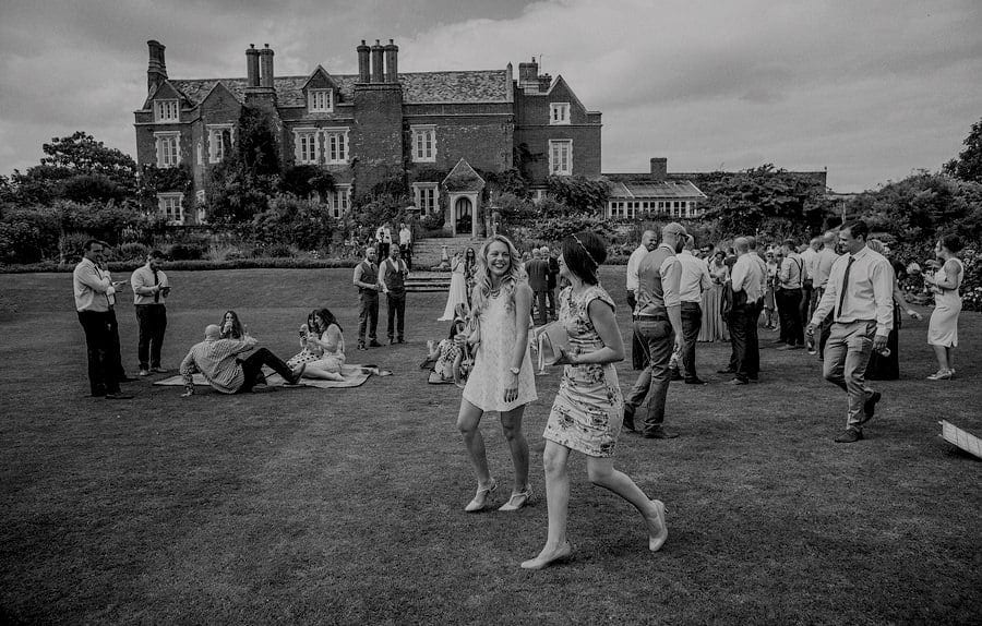 Wedding guests smile at each other as they walk across the back lawn at Childerley Estate in Cambridgeshire