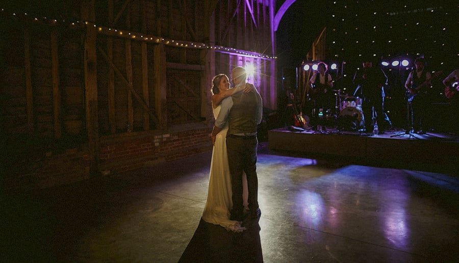 The bride and groom embrace each other on the dancefloor in the old barn at Childerley