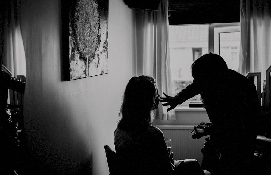 The make up artist applies foundation onto the brides face