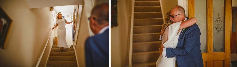 The bride walks down the stairs of her parents house and greets her father