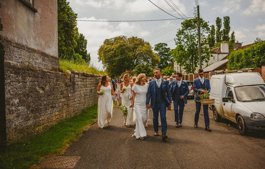 The bride and groom leave the church and walk down the street