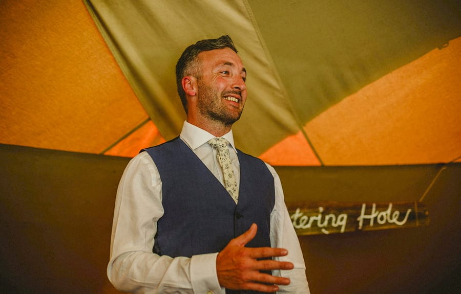 The groom shares a joke with everyone in the tipi