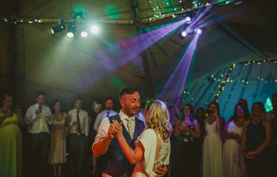 The groom smiles at the bride on the dancefloor during the first dance
