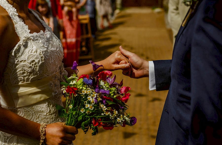 The groom holds the brides hand during the outdoor wedding ceremony