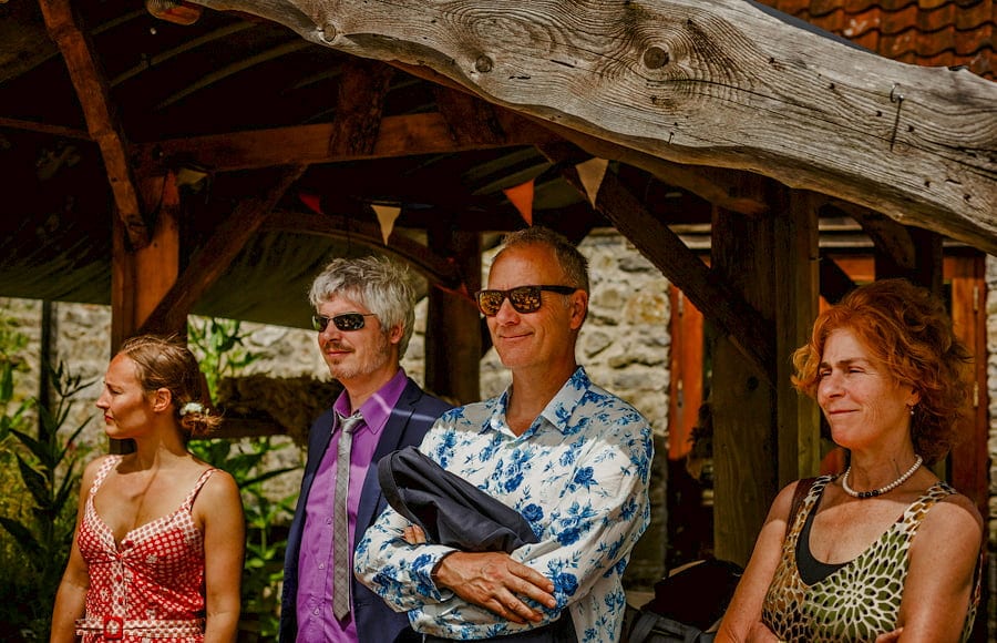 Wedding guests watch the wedding ceremony under a wooden canopy