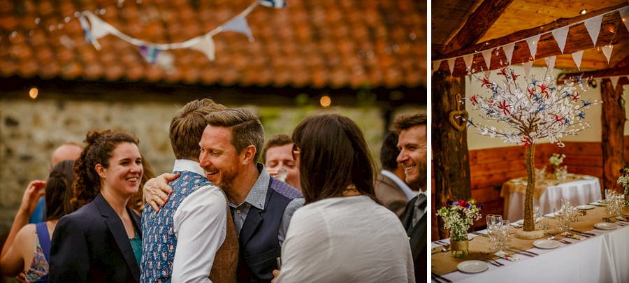 A wedding guest puts his arm around the groom in the courtyard at Fernhill Farm
