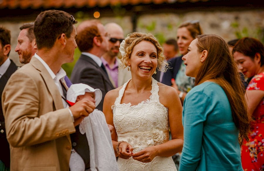 The bride laughs with friends in the courtyard at Fernhill Farm