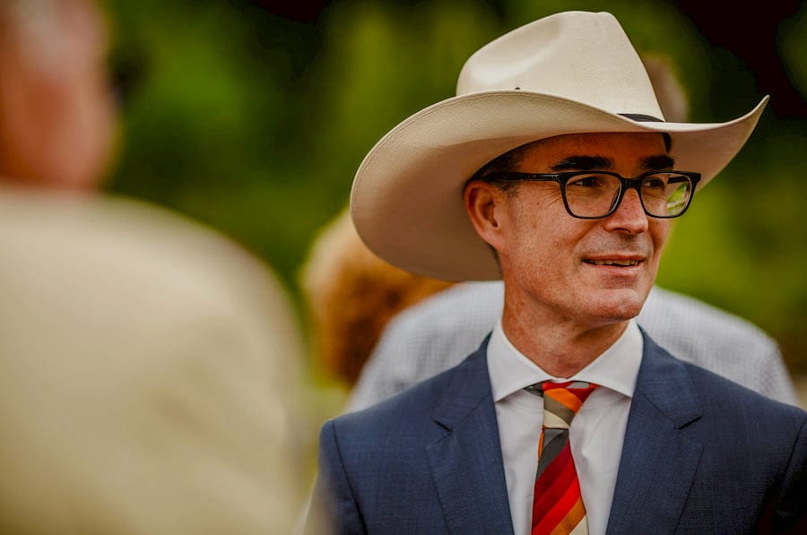 A wedding guest wears a white hat