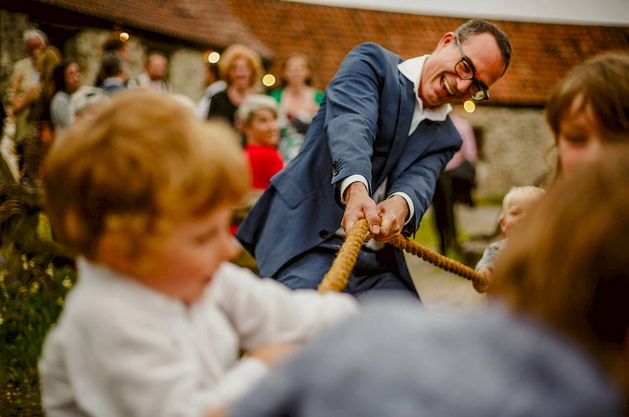 A wedding guest pulls a rope with children in the courtyard at Fernhill Farm