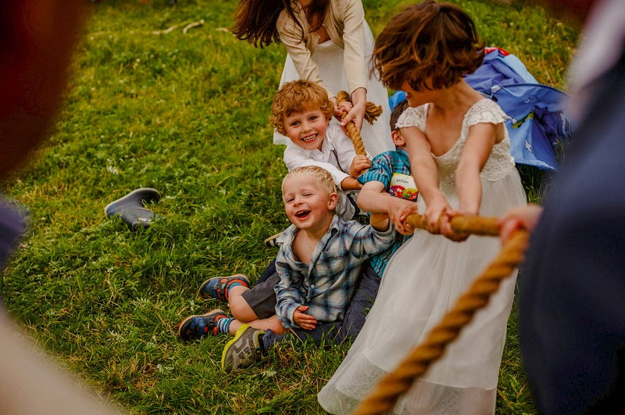 Children lie on the floor and laugh as they hold onto a rope